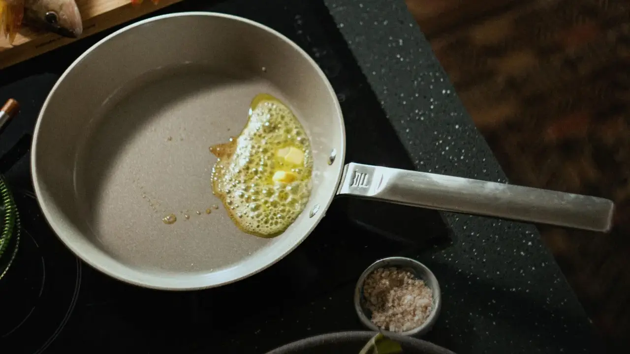 Eine beschichtete Pfanne reinigen: Butter schmilzt und blubbert, bereit für den Fisch.