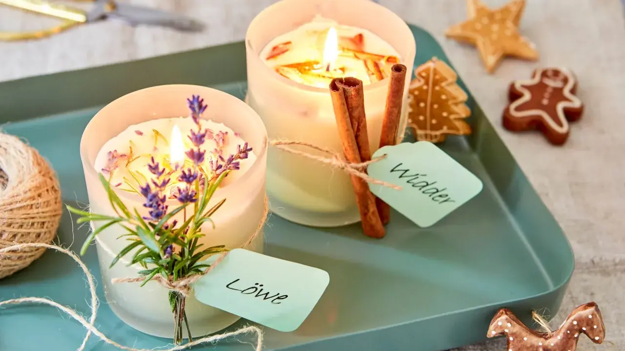 Zwei selbstgemachte Duftkerzen mit Lavendel und Zimtstangen, verziert mit Lebkuchen.