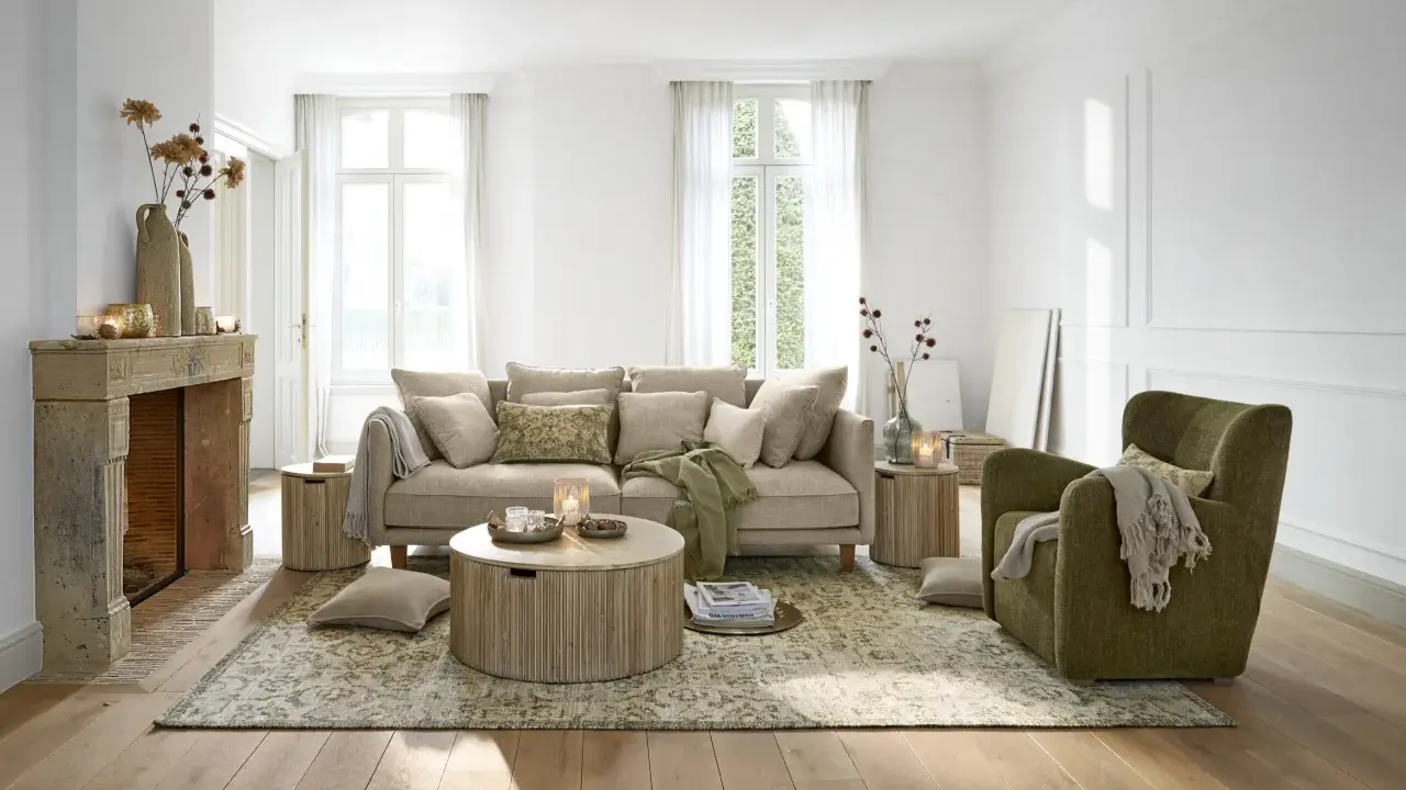 Gemütliches **interior wohnzimmer** mit beigem Sofa, grünem Sessel, Kamin und Holzboden.