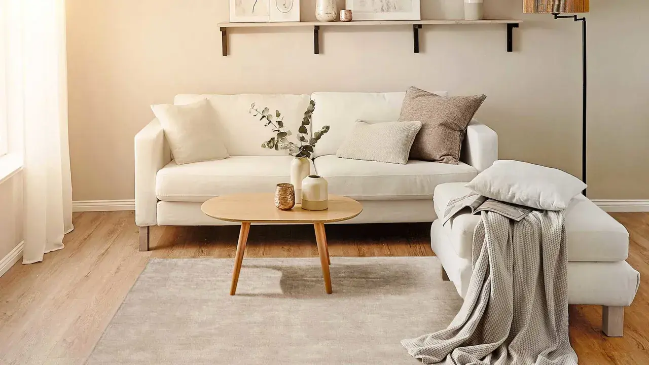 Ein helles Wohnzimmer mit weißem Sofa, Holztisch und Teppich. Perfekt für minimalistisch wohnen.