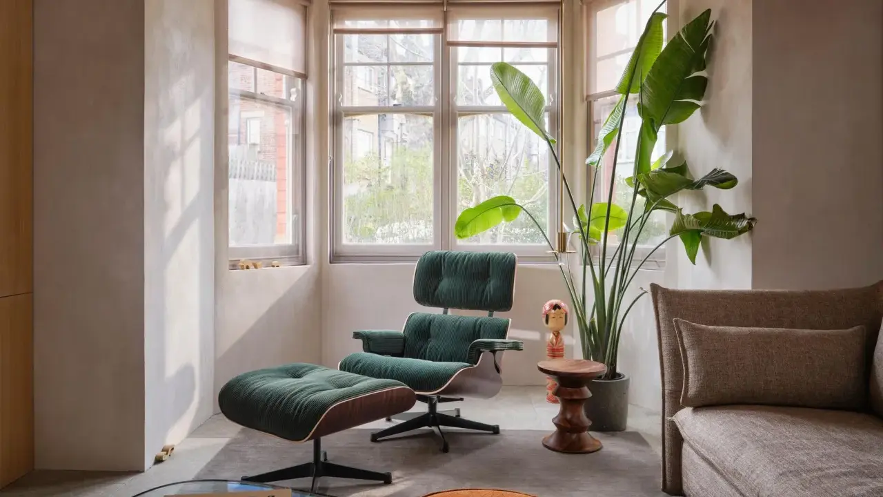 Gemütliche Ecke im midcentury stil mit einem grünen Cord-Sessel und Hocker, daneben eine große Zimmerpflanze und ein Beistelltisch.