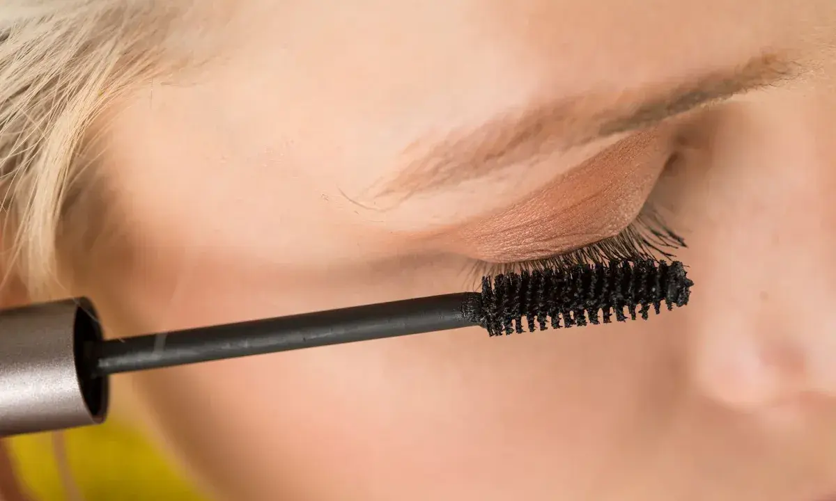 Ein Auge wird mit Mascara für ein leichtes Sommer Make-up betont. Die Bürste trennt und verlängert die Wimpern.