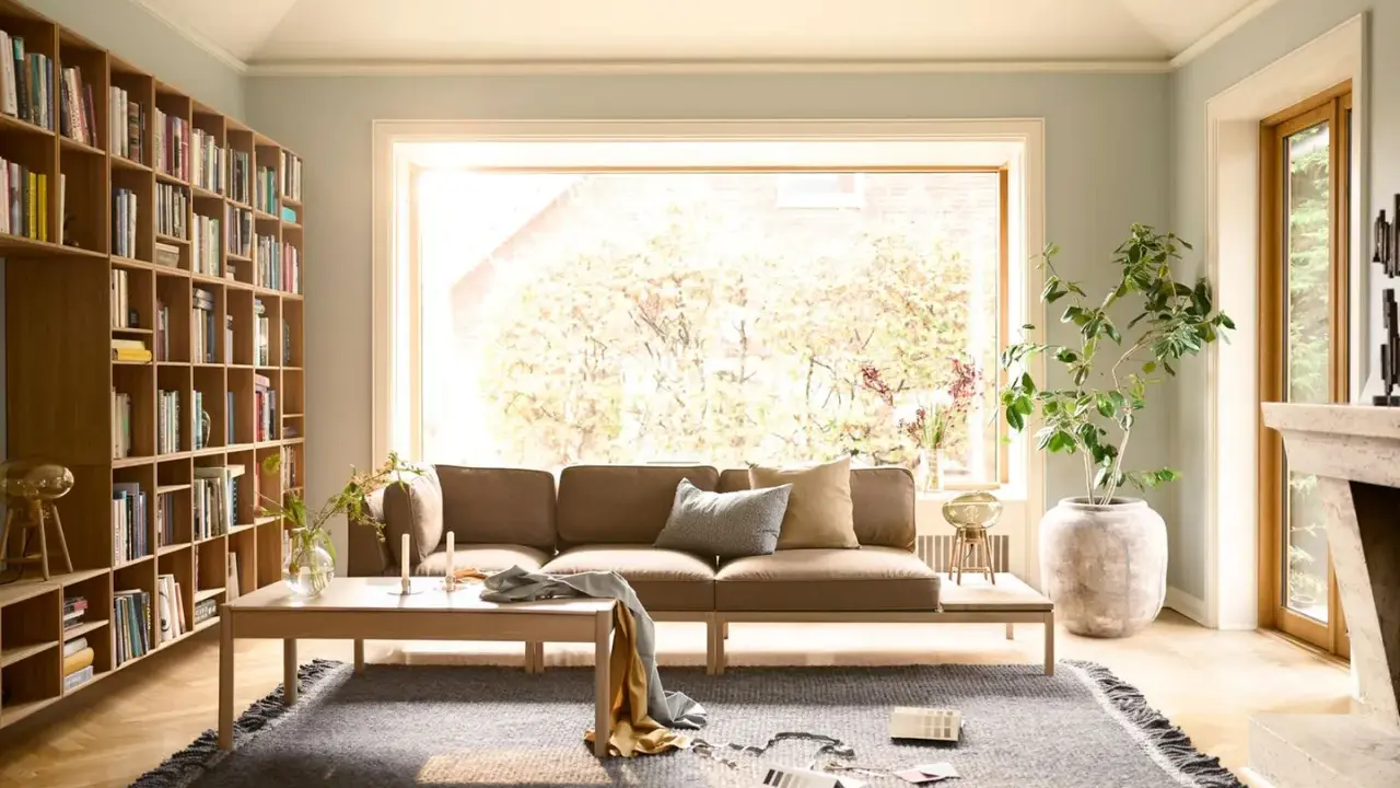 Gemütliche Anordnung Sofa Wohnzimmer mit Bücherregal, Kamin und großem Fenster.