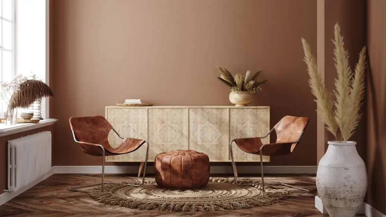 Ein gemütliches Wohnzimmer im Boho-Stil mit zwei Ledersesseln, einem runden Teppich, einem Sideboard und Trockenblumen.