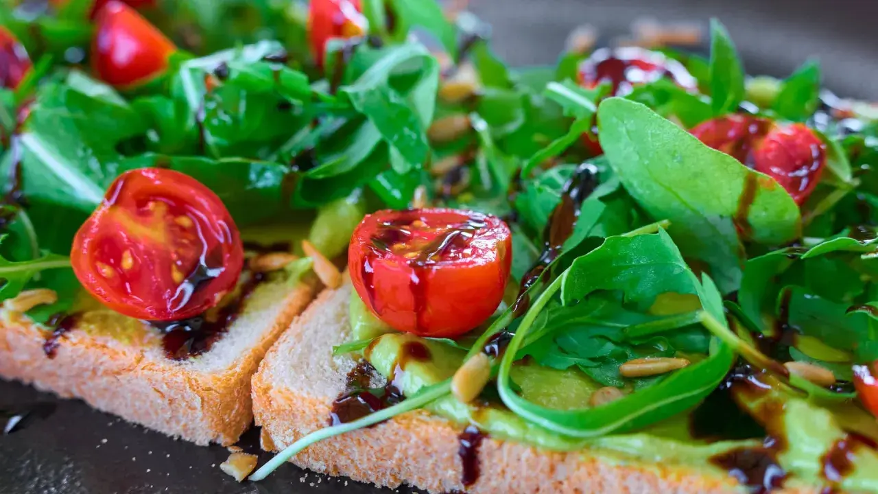 Leckere Bruschetta mit Avocado, Tomaten und Rucola, beträufelt mit Balsamico. So lassen sich Balsamico-Flecken entfernen: schnell handeln!