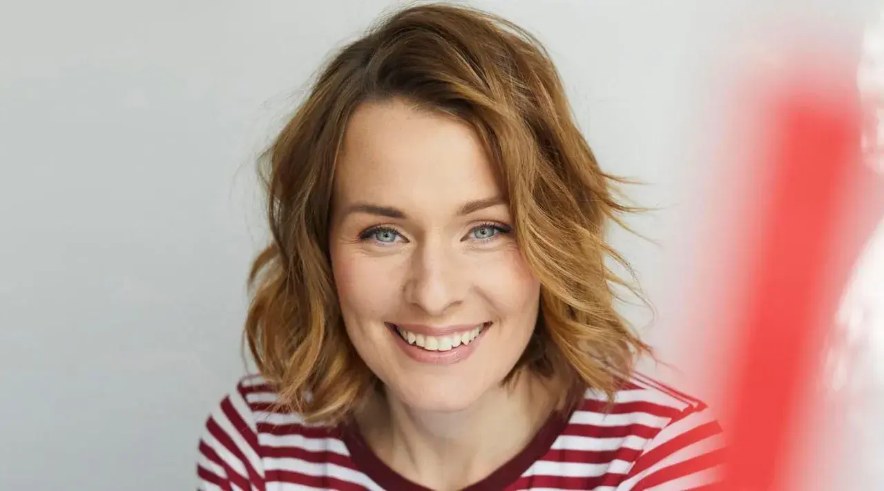 Eine Frau mit schulterlangen, welligen Haaren und einem strahlenden Lächeln. Diese Frisuren 2026 halblang sind modern und schmeichelhaft.