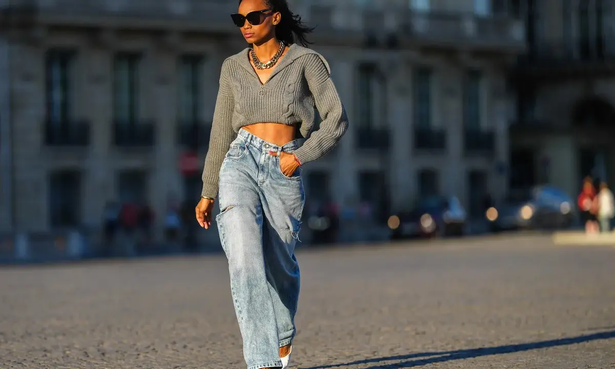 Stylische Frau in weit geschnittenen Jeans und kurzem Strickpullover, die zeigt, wie man wide leg jeans kombinieren kann.