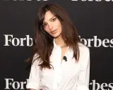 Emily Ratajkowski mit langen, gestuften Haaren und einem weißen Hemd vor einem Forbes-Banner.