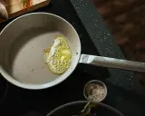 Eine beschichtete Pfanne reinigen: Butter schmilzt und blubbert, bereit für den Fisch.
