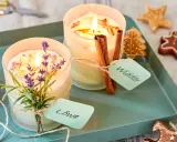 Zwei selbstgemachte Duftkerzen mit Lavendel und Zimtstangen, verziert mit Lebkuchen.