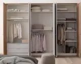 Ein offener Kleiderschrank, bereit zum Ausmisten. Ordentlich sortierte Kleidung auf Kleiderbügeln und gefaltete Textilien auf den Regalen.