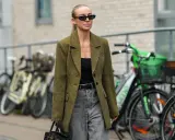 Stilvolle Frau mit Sonnenbrille und kariertem Blazer, die zeigt, wie man graue Jeans kombiniert.