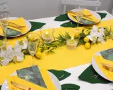 Sommerliche tischdeko mit zitronen, Orchideen und grünen Blättern. Kerzen in Gläsern sorgen für stimmungsvolles Licht.