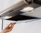 Hand entfernt Fettfilter der Dunstabzugshaube, um die klebrige Dunstabzugshaube reinigen zu können.