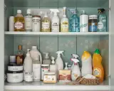 Omas Haushaltstipps: Eine Sammlung von Reinigungsmitteln in einem Schrank, von Sprühflaschen bis zu großen Behältern.