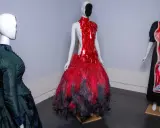 Drei Schaufensterpuppen präsentieren extravagante Kleider, die an das Met Gala Thema erinnern: eines in Grün im viktorianischen Stil, eines in Rot mit Federn und eines mit anatomischem Druck.