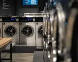 Reihe von Waschmaschinen in einem Waschsalon. Hoffentlich stinkt keine Waschmaschine nach Kanal.