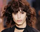 Ein Model mit einem lässigen shag cut und dunklen, welligen Haaren.
