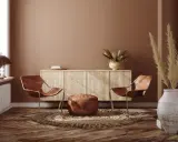 Ein gemütliches Wohnzimmer im Boho-Stil mit zwei Ledersesseln, einem runden Teppich, einem Sideboard und Trockenblumen.