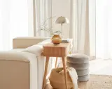 Gemütliches Wohnzimmer mit beigem Sofa, Holztisch, Lampe und Korb. Die helle Atmosphäre vermittelt das Gefühl von Hygge Bedeutung: Wohlbefinden und Gemütlichkeit.