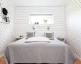 Gemütliches Schlafzimmer 10 qm einrichten: Sternen-Tapete, graue Decke, Nachttische und ein Bett mit Kissen.
