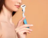 Eine Frau hält einen Rasierer, bereit für die Intimrasur.