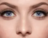 Blaue Augen mit dramatisch aufklebbaren Wimpern und goldenem Lidschatten.