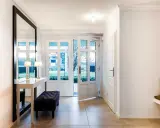 Moderner Flur mit großem Spiegel, Konsole, Bank und Glastüren nach draußen.