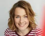 Eine Frau mit schulterlangen, welligen Haaren und einem strahlenden Lächeln. Diese Frisuren 2026 halblang sind modern und schmeichelhaft.