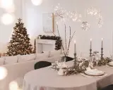 Festlich gedeckter Tisch mit Kerzen und Weihnachtbaum. Die Frage "ab wann weihnachtsdeko" stellt sich hier nicht, denn die Deko ist bereits da!