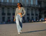 Stylische Frau in weit geschnittenen Jeans und kurzem Strickpullover, die zeigt, wie man wide leg jeans kombinieren kann.