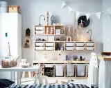 Ein schmal eingerichtetes Kinderzimmer mit viel Holz und weißen Aufbewahrungsboxen. Spielzeugtiere und Bauklötze sind ordentlich verstaut.