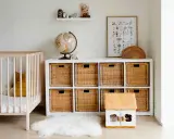 Ordentliches Kinderzimmer mit Gitterbett, Spielzeugkiste, Globus und Wandbild. Alles griffbereit für den Nachwuchs.