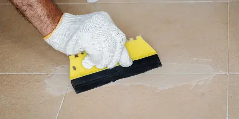 Mit einem gelben Spachtel werden die **Fliesen Fugen reinigen** und mit neuem Material gefüllt.