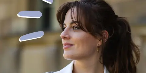 Frau mit rundem Gesicht und Curtain Bangs, trägt weißen Blazer.