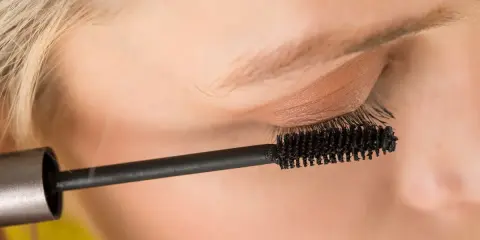 Ein Auge wird mit Mascara für ein leichtes Sommer Make-up betont. Die Bürste trennt und verlängert die Wimpern.