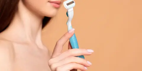 Eine Frau hält einen Rasierer, bereit für die Intimrasur.