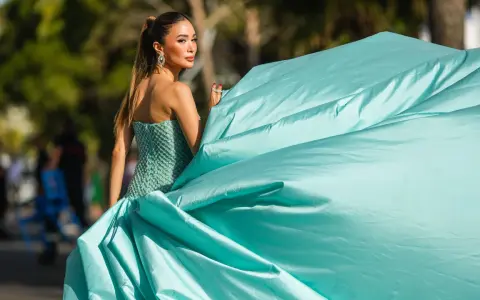 Elegante Dame im mintgrünen Ballkleid, das den Black Tie Dresscode für Damen perfekt verkörpert. Ihr Kleid weht im Wind.