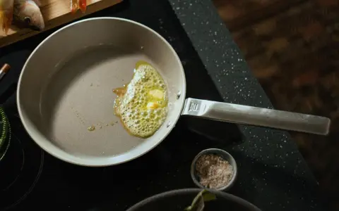 Eine beschichtete Pfanne reinigen: Butter schmilzt und blubbert, bereit für den Fisch.