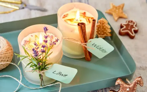 Zwei selbstgemachte Duftkerzen mit Lavendel und Zimtstangen, verziert mit Lebkuchen.
