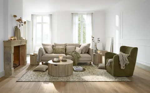 Gemütliches **interior wohnzimmer** mit beigem Sofa, grünem Sessel, Kamin und Holzboden.