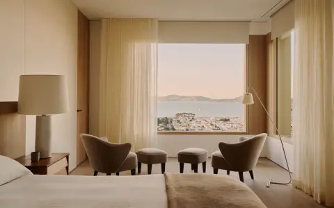 Ein Schlafzimmer mit Blick auf die Stadt und das Meer, gestaltet im Stil einer Feng Shui Wohnung. Sanfte Farben und natürliche Materialien schaffen Harmonie.