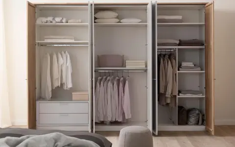 Ein offener Kleiderschrank, bereit zum Ausmisten. Ordentlich sortierte Kleidung auf Kleiderbügeln und gefaltete Textilien auf den Regalen.