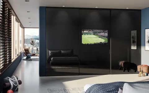 Ein moderner Kleiderschrank mit Spiegeltüren beherbergt einen integrierten Fernseher im Schlafzimmer, der ein Tennismatch zeigt.