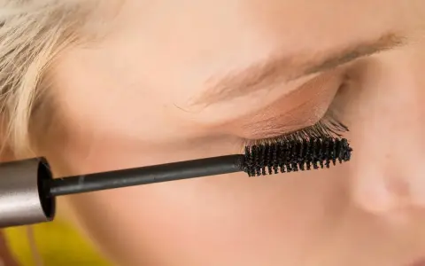 Ein Auge wird mit Mascara für ein leichtes Sommer Make-up betont. Die Bürste trennt und verlängert die Wimpern.