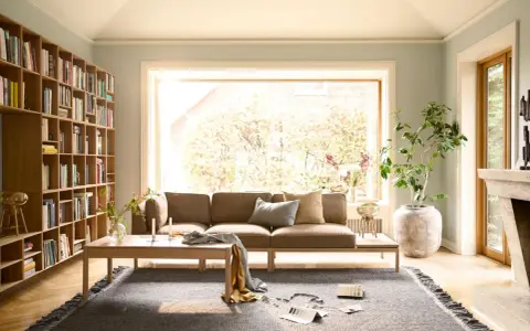 Gemütliche Anordnung Sofa Wohnzimmer mit Bücherregal, Kamin und großem Fenster.