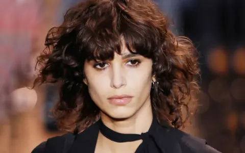 Ein Model mit einem lässigen shag cut und dunklen, welligen Haaren.