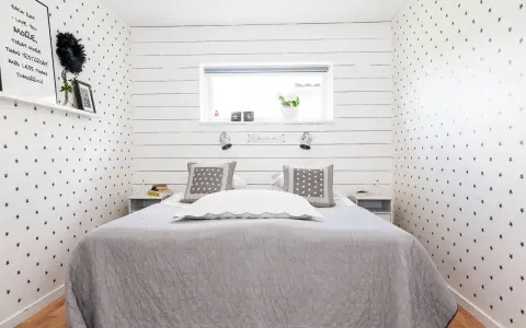 Gemütliches Schlafzimmer 10 qm einrichten: Sternen-Tapete, graue Decke, Nachttische und ein Bett mit Kissen.