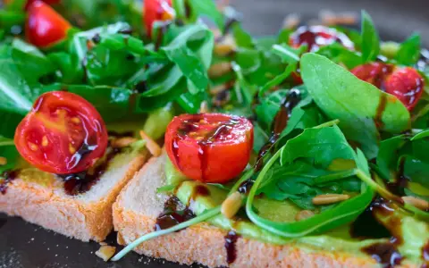 Leckere Bruschetta mit Avocado, Tomaten und Rucola, beträufelt mit Balsamico. So lassen sich Balsamico-Flecken entfernen: schnell handeln!