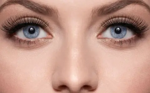 Blaue Augen mit dramatisch aufklebbaren Wimpern und goldenem Lidschatten.